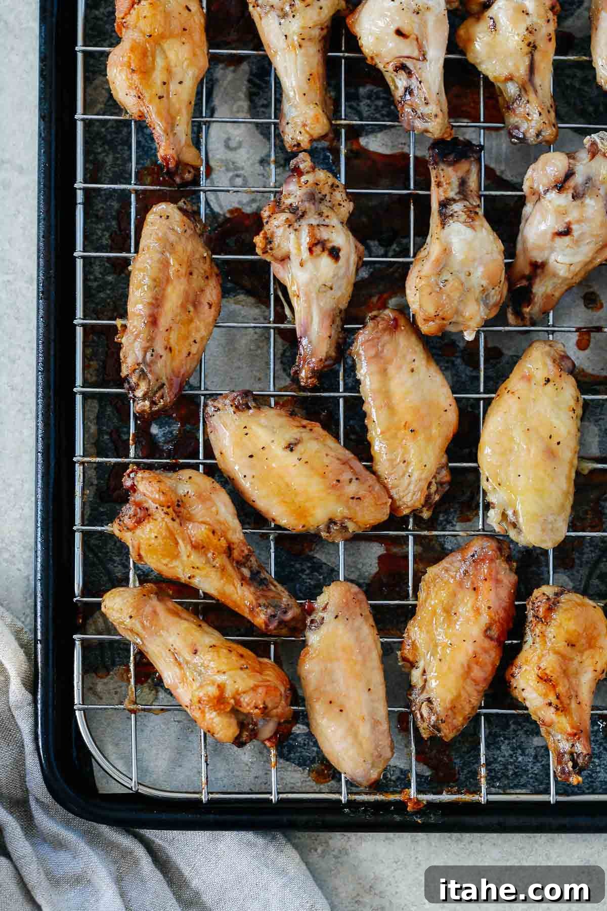 Crispy chicken wings perfectly arranged on a wire rack over a baking sheet, showcasing their golden-brown color.