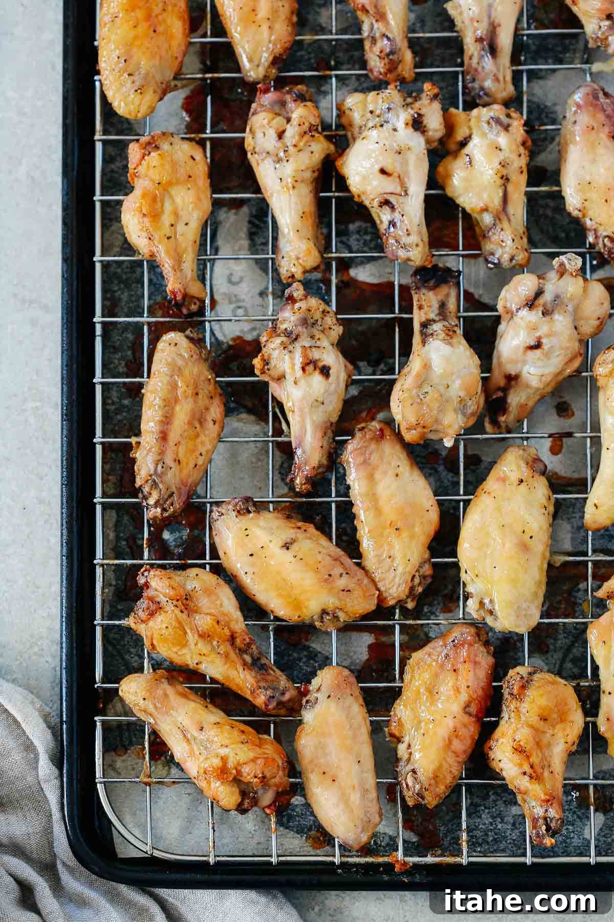 A close-up view of multiple perfectly cooked, golden-brown chicken wings resting on a metal cooling rack.
