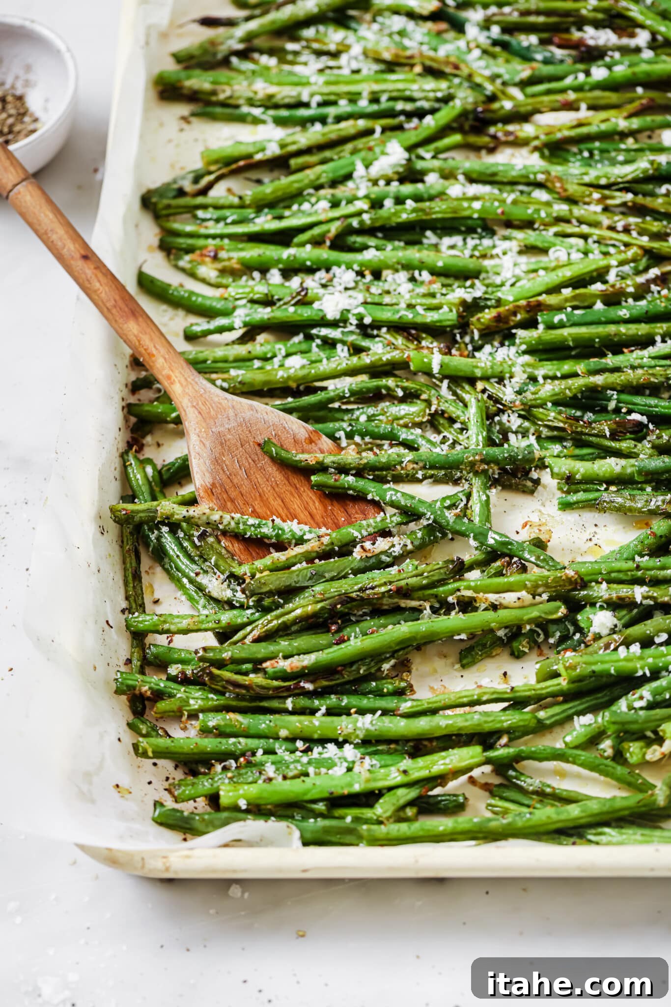 Close up of a baking sheet filled with perfectly roasted parmesan green beans.