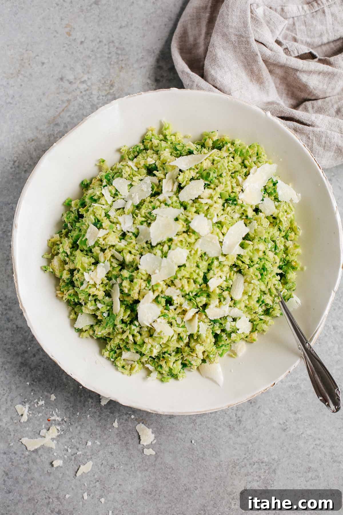 Crispy Parmesan Brussels Sprouts Salad 2 overhead view of a plate of Parmesan Brussels Sprouts Salad, showcasing its vibrant green color and generous parmesan shavings.