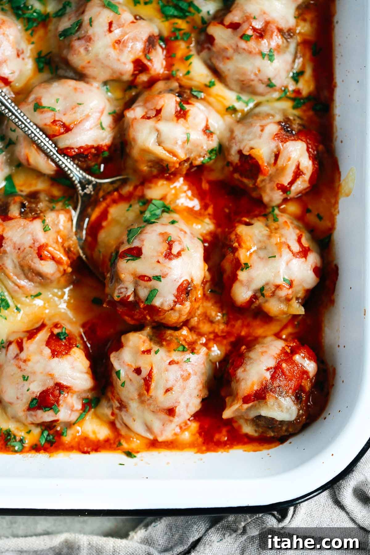 Hearty Meatball Bake 2 Close up of Baked Meatballs Casserole with a spoon lifting one meatball