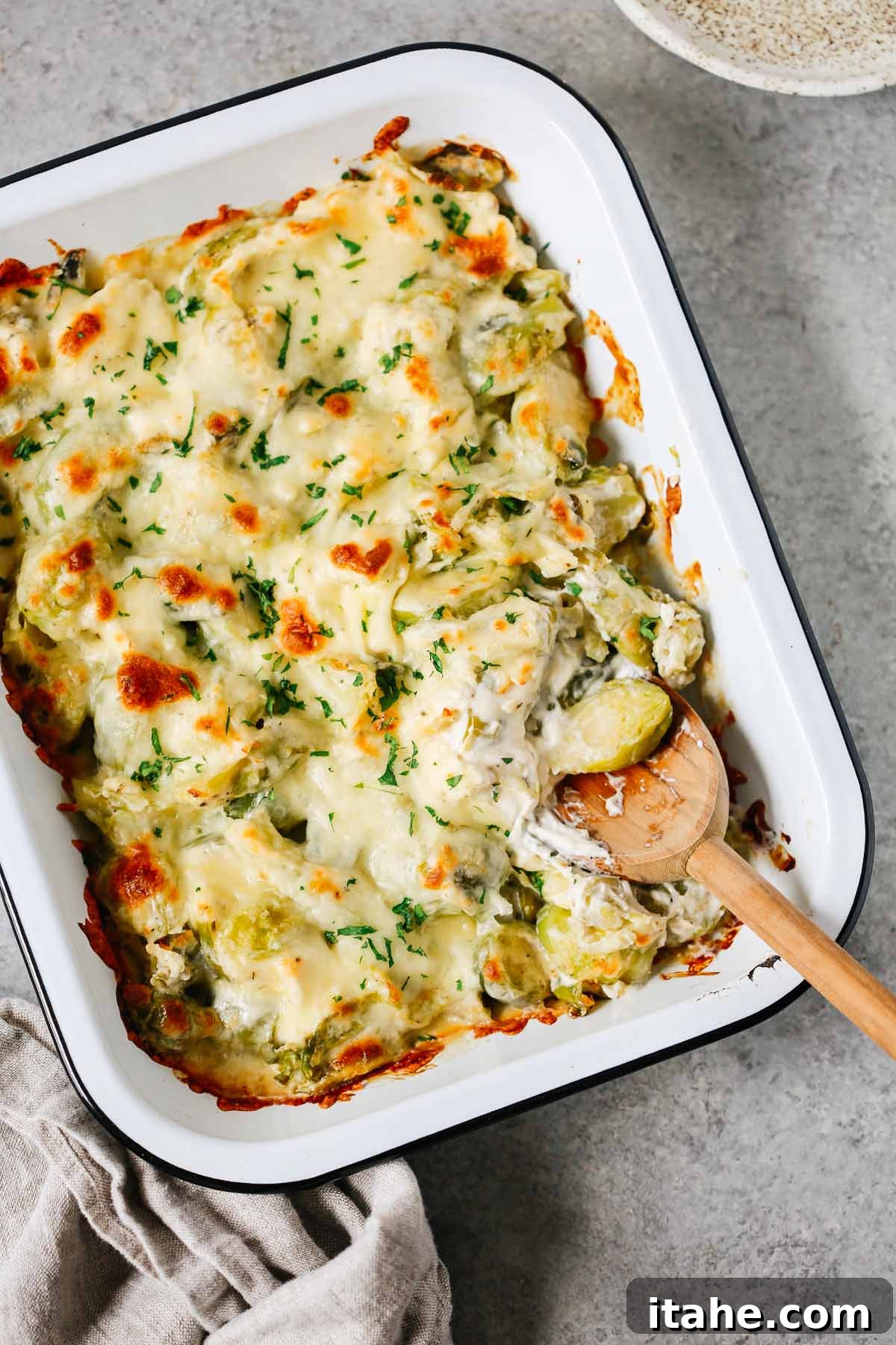 Creamy Brussels Sprouts Gratin 2 Brussels sprouts casserole recipe in a baking dish with a wooden spoon inside.