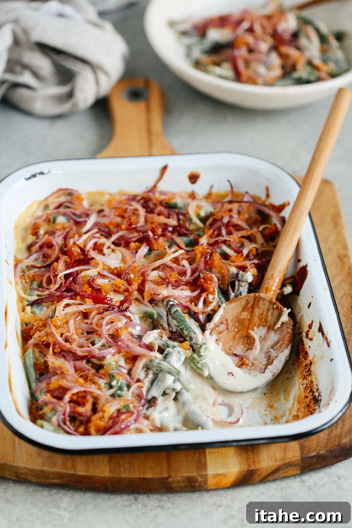 Wholesome Green Bean Casserole 11 Angled image of Healthier Green Bean Casserole Recipe with a wooden spoon scooping a portion out.