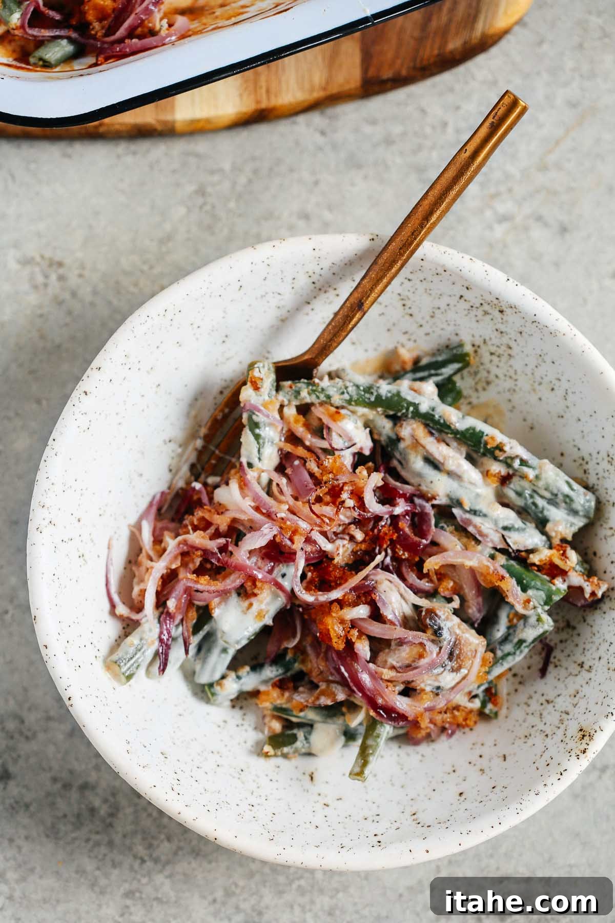 Wholesome Green Bean Casserole 10 Overhead photo of Healthier Green Bean Casserole Recipe in a white bowl with a gold fork inside.