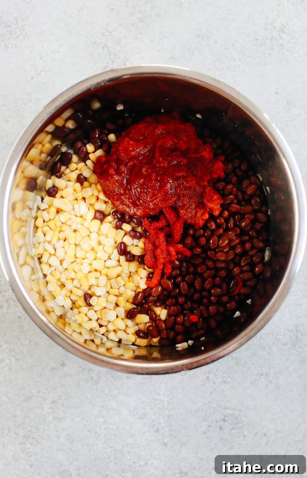 Instant Pot Fiesta Chicken Soup 4 The Instant Pot liner filled with a colorful mix of ingredients including corn, black beans, tomato sauce, and tomato paste, ready for pressure cooking.