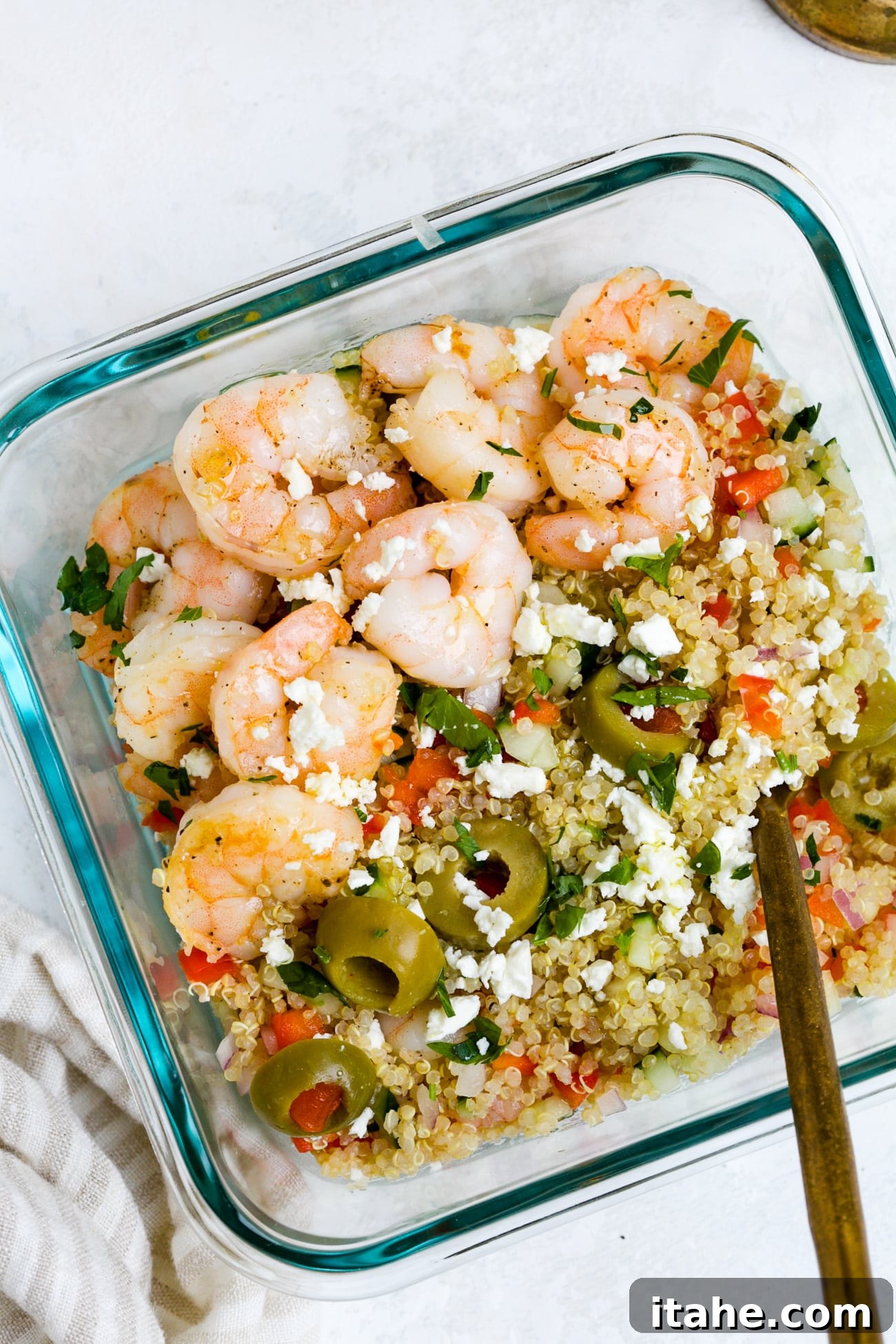 Overhead view of shrimp quinoa salad in a glass meal-prep bowl.