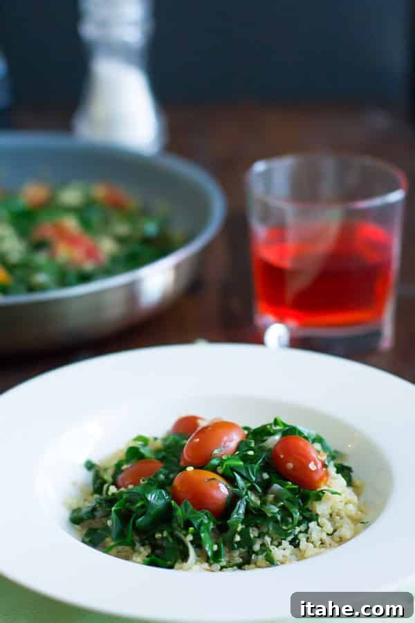 Bowl of warm collard quinoa salad with fresh cherry tomatoes