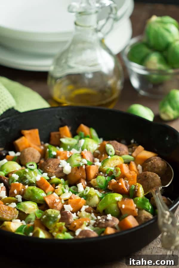 close up of a cast iron skillet containing sweet potato and brussels sprouts