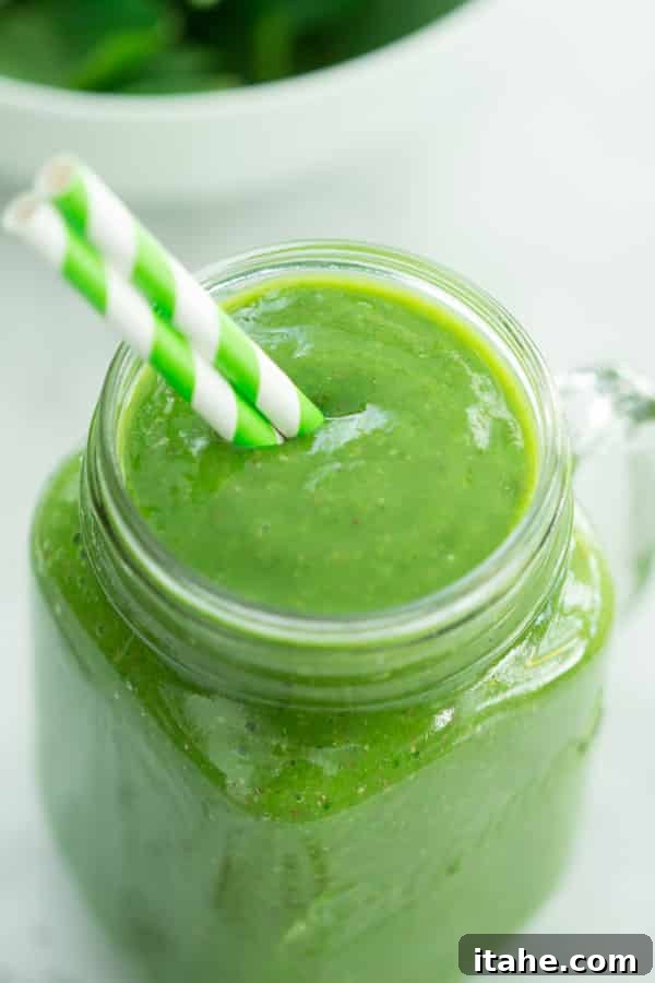 Nutrient-Rich Mango Green Smoothie for a Healthy Start Vibrant Mango Green Smoothie in a glass with a straw, surrounded by fresh mango and spinach