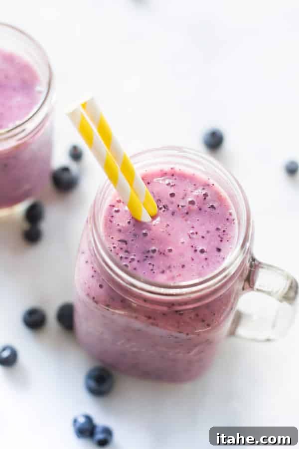 Tropical Mango Green Blend 3 Creamy Blueberry Banana Smoothie in a glass, garnished with fresh berries