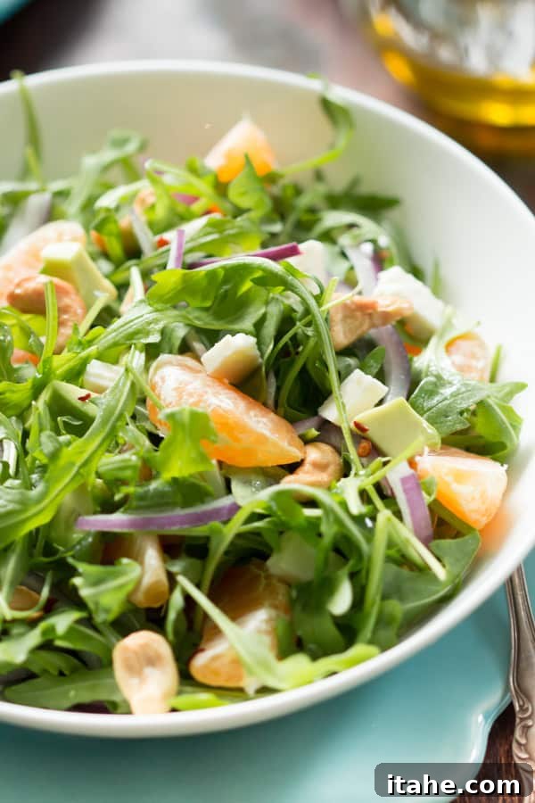 Close-up of fresh clementine segments and peppery arugula in a healthy winter salad.