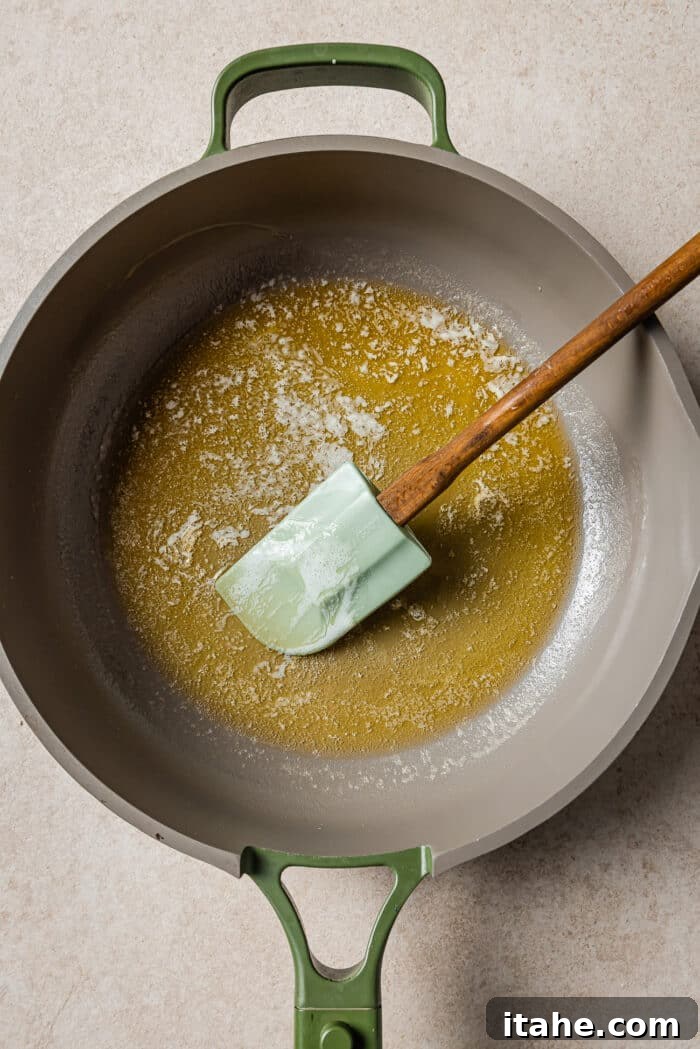 Creamy Peanut Butter Flapjacks 4 Melted butter in a skillet with a rubber spoon on the side.