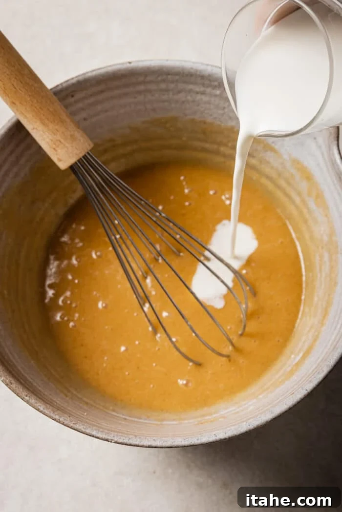 Creamy Peanut Butter Flapjacks 6 Milk is added to the bowl of wet pancake ingredients.