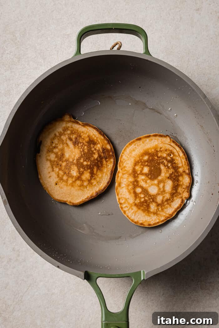 Creamy Peanut Butter Flapjacks 9 Two golden brown peanut butter pancakes in a skillet.