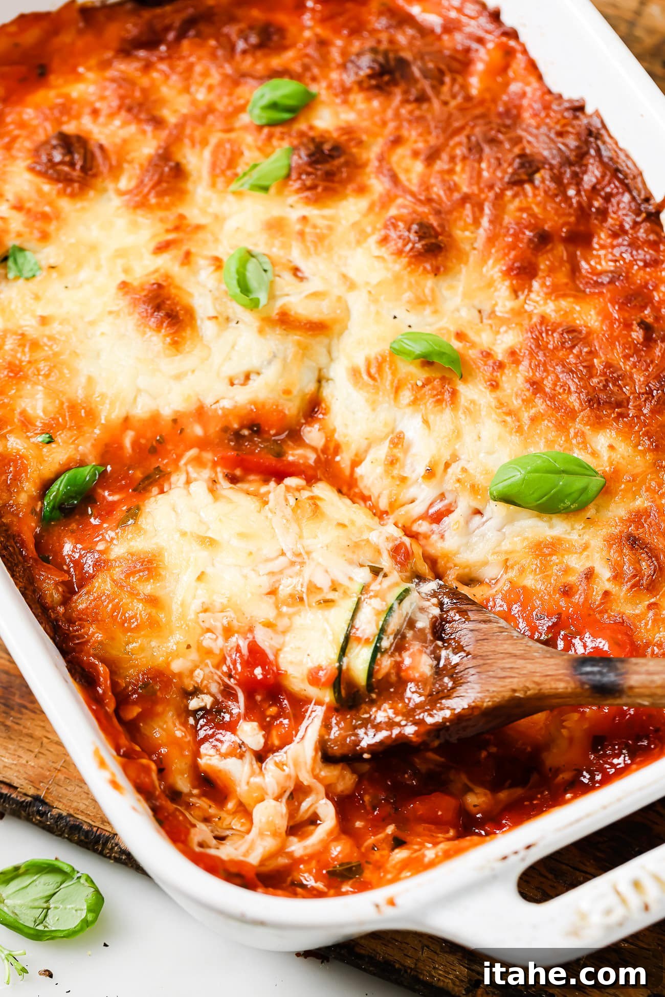 An overhead view of freshly baked zucchini lasagna rolls, golden and bubbling, in a baking dish.
