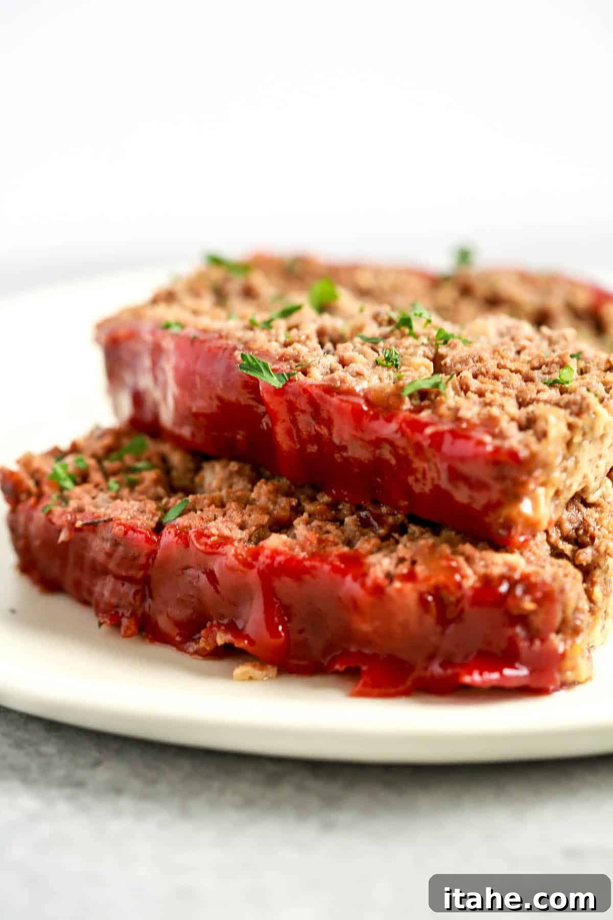 close up image: two slices of healthy meatloaf with tomato sauce on top