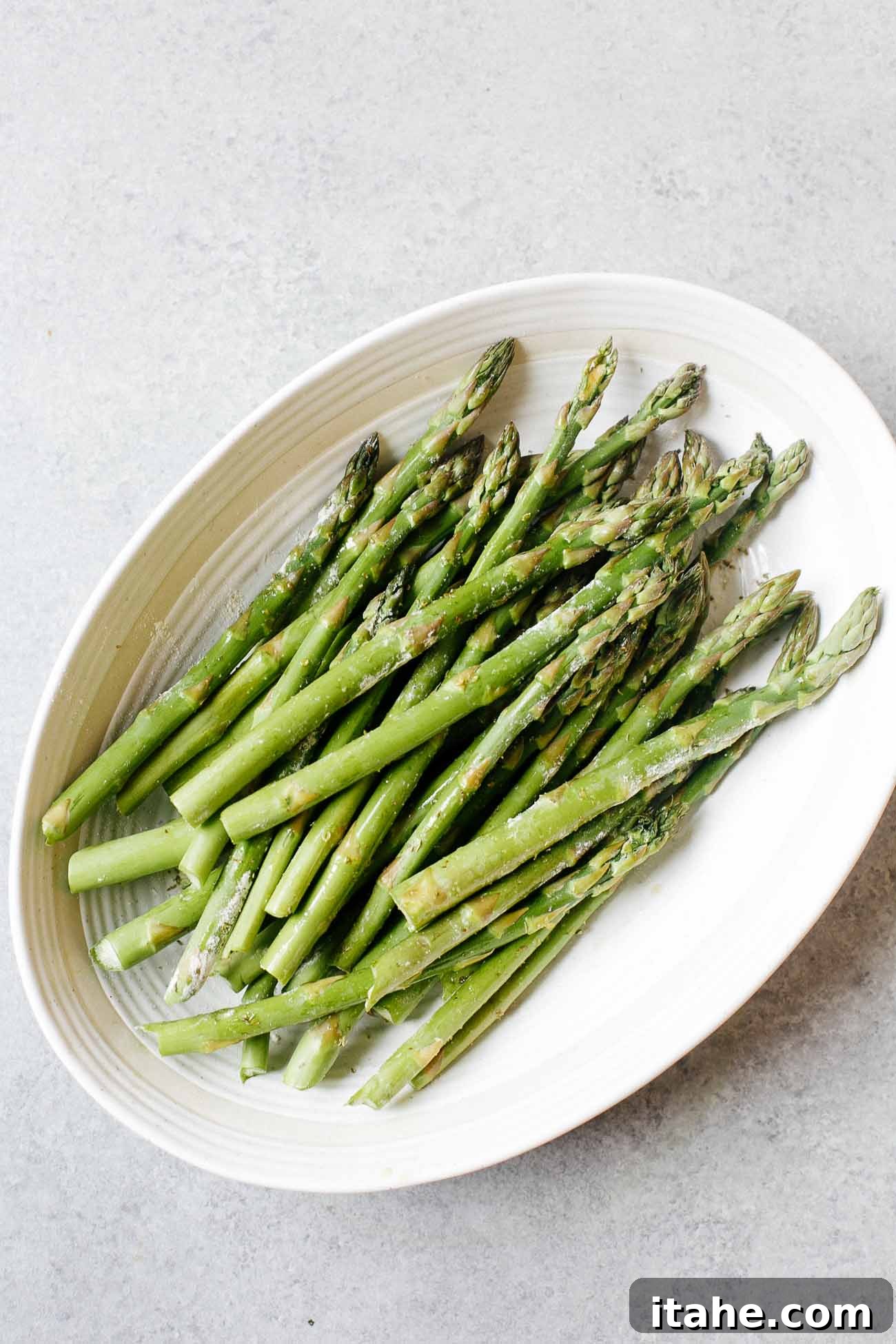 Overhead view of trimmed asparagus in a white casserole dish
