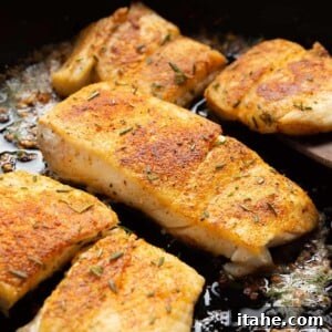 closeup of flaky garlic butter halibut fish in a cast iron skillet
