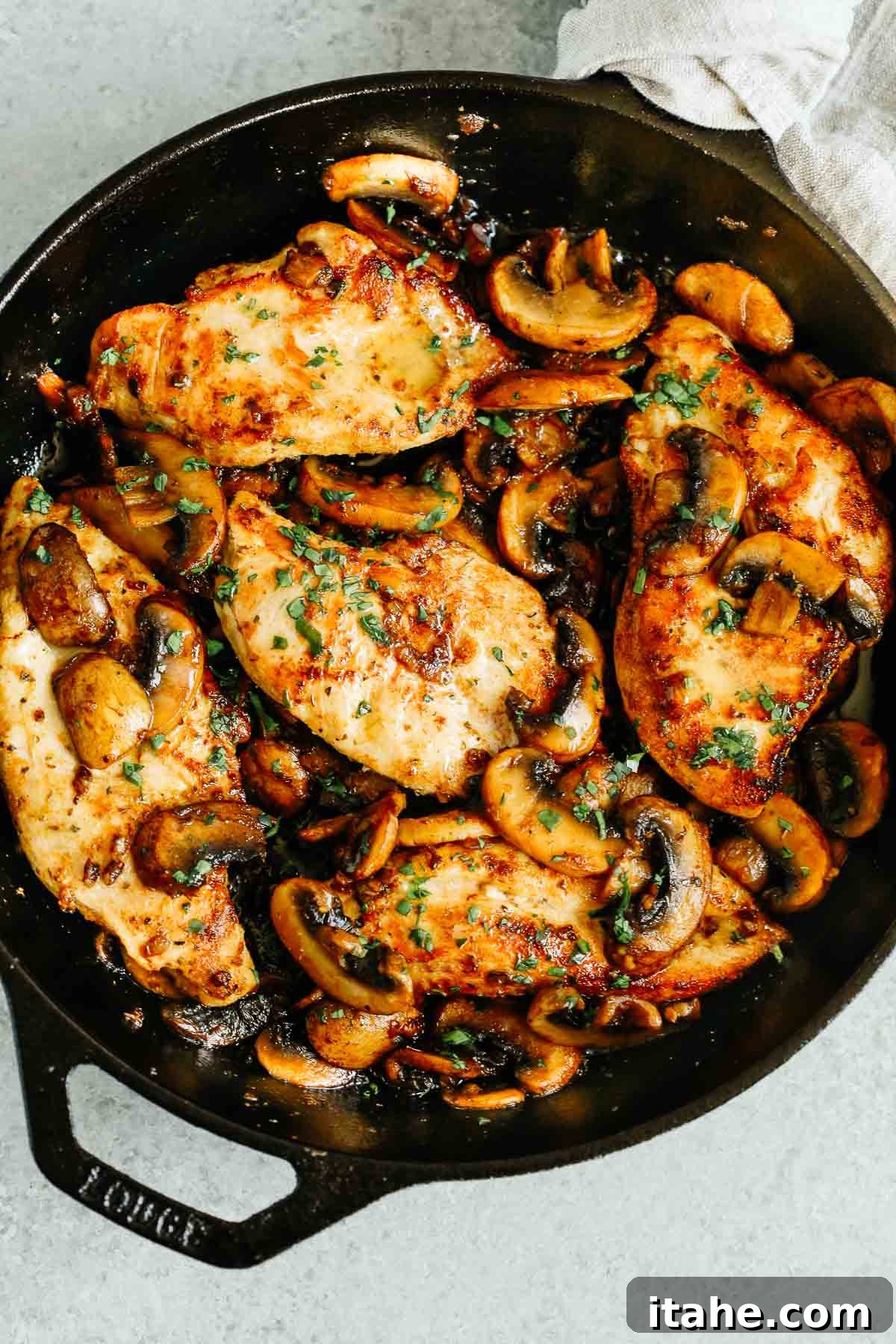 overhead photo of cooked chicken breasts and mushrooms in a cast iron skillet