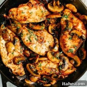 overhead photo of cooked chicken breasts and mushrooms in a cast iron skillet