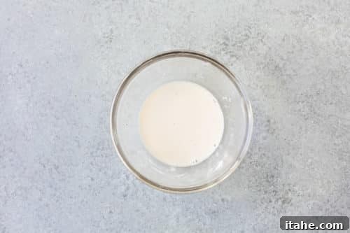 Arrowroot flour mixed with water in a small glass bowl, forming a slurry for thickening.