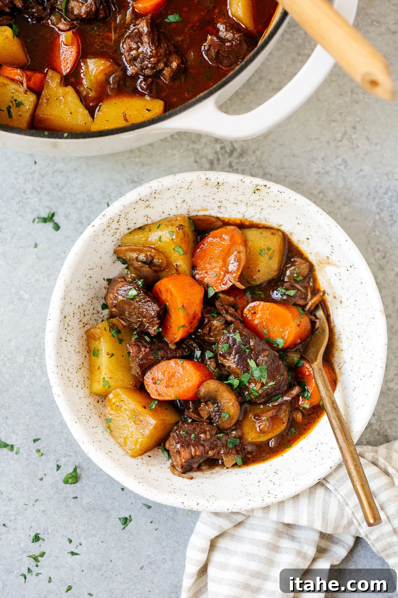 A serving of Dutch Oven Beef Stew in a white bowl, garnished with fresh herbs, ready to be enjoyed.