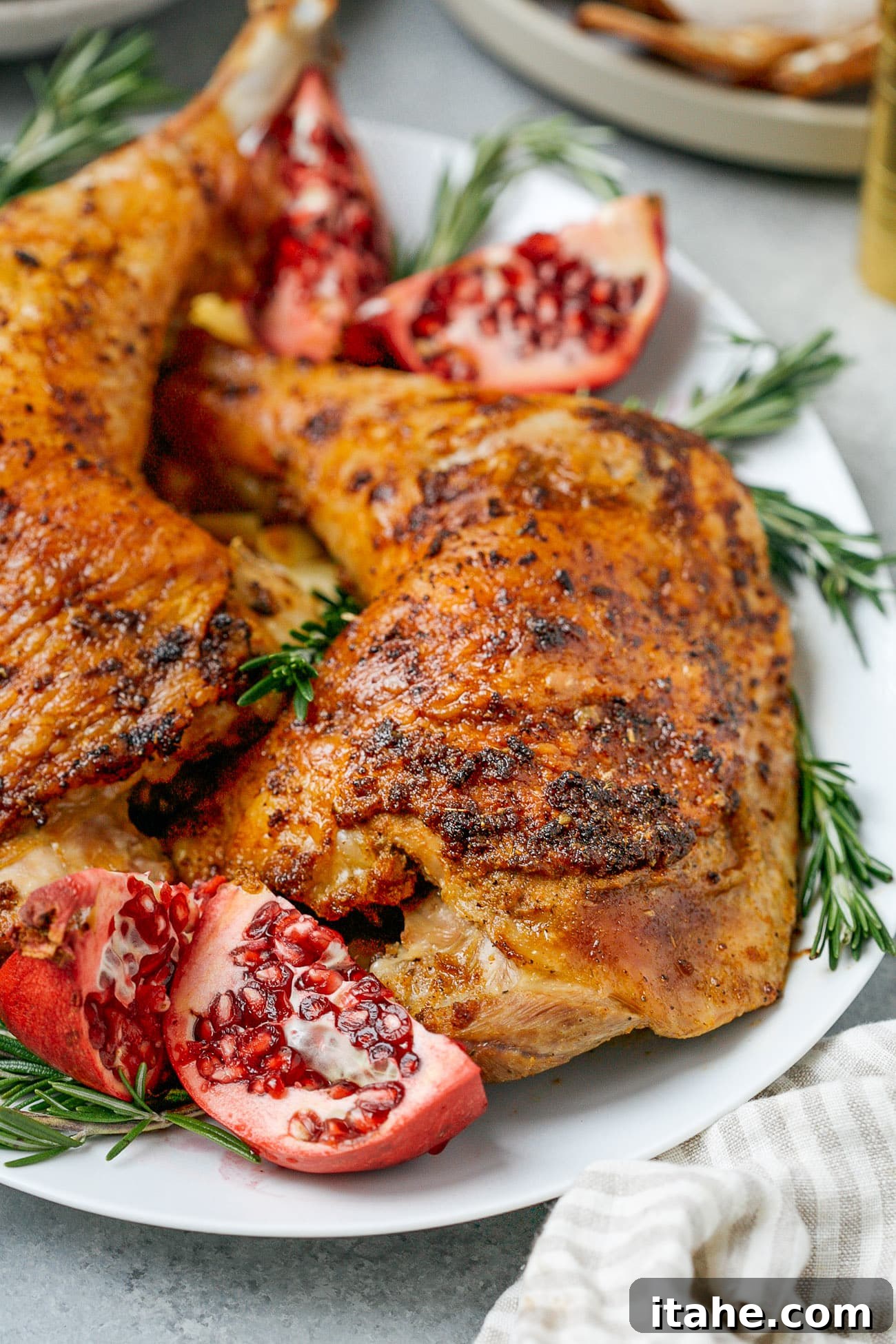 Close up of a roasted turkey leg with fresh rosemary and pomegranate.