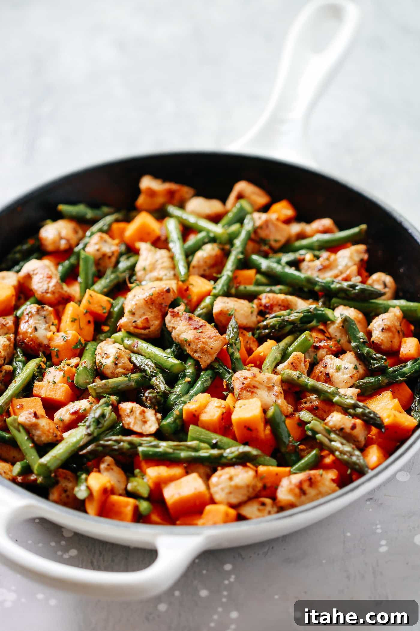 Golden Chicken Sweet Potato Bake 2 A vibrant close-up of the delicious One-Pan Chicken Sweet Potato and Asparagus Skillet with golden chicken pieces.