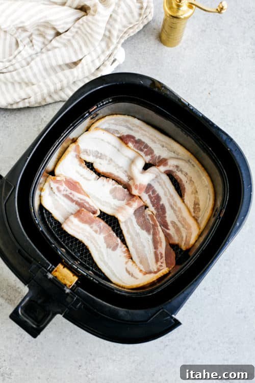 overhead view of raw bacon inside of a air fryer basket