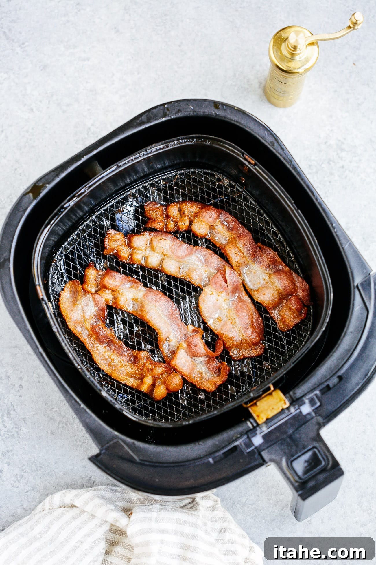 overhead view of cooked bacon inside of a air fryer basket 