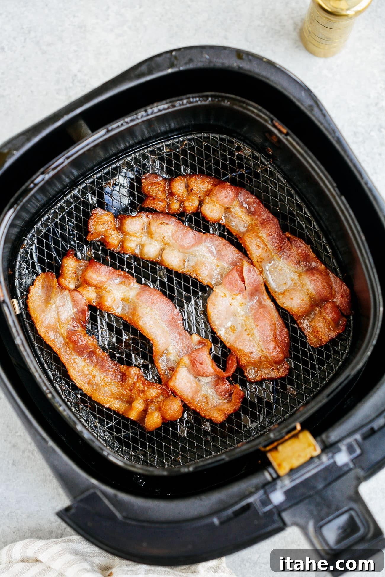 overhead view of cooked bacon inside of a air fryer basket 
