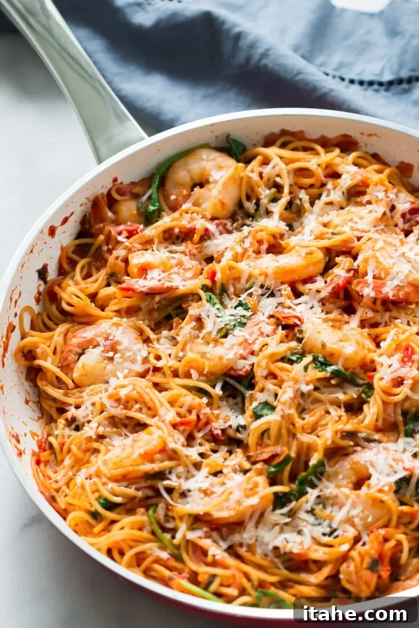 Overhead view of a white pan with spaghetti and shrimp, garnished with parsley.