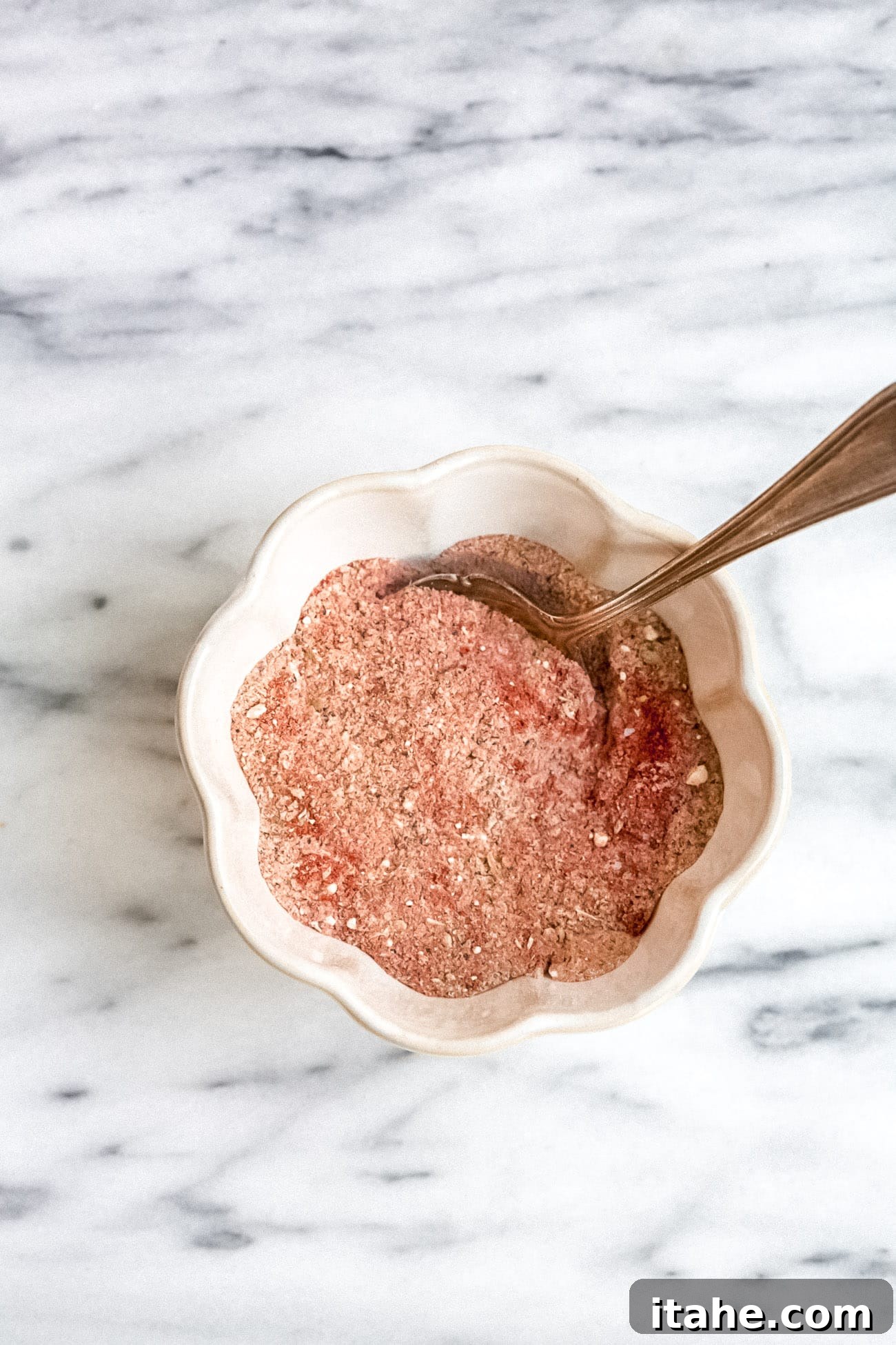 Craft Your Own Cajun Spice Blend 4 A small, elegant bowl overflowing with rich, vibrant homemade Cajun seasoning, captured from an overhead perspective, showcasing its finely ground texture and deep color.
