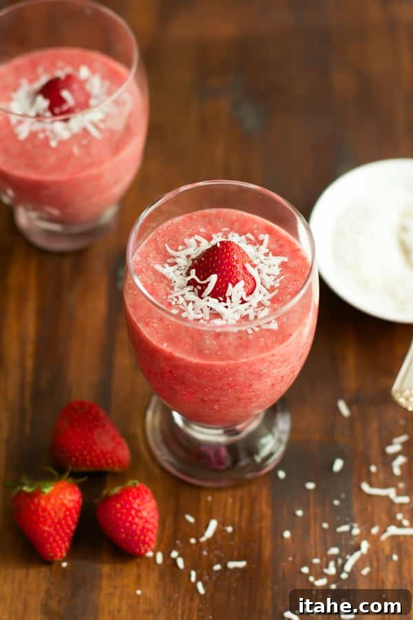 Two servings of strawberry chia pudding topped with shredded coconut and a fresh strawberry slice.