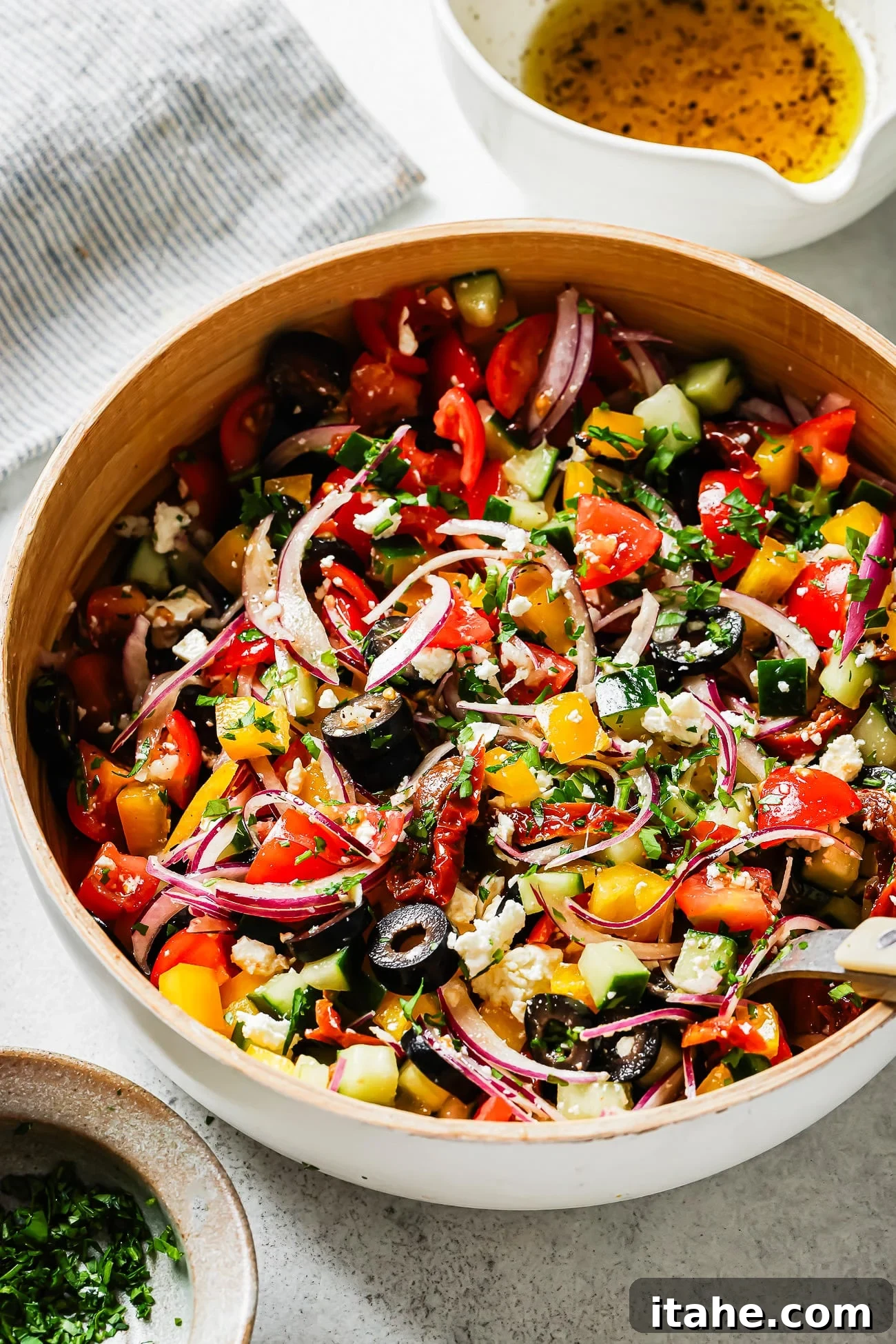 A beautifully arranged Mediterranean Salad in a pristine white bowl, viewed from above, showcasing its vibrant array of fresh vegetables and crumbled feta cheese.