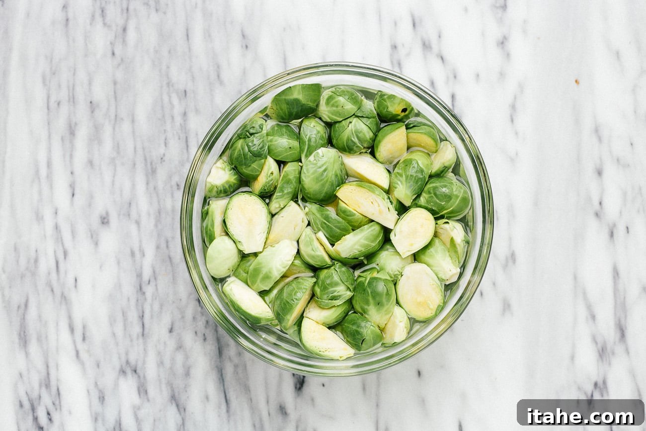 Brussels sprouts soaking in a bowl of water, preparing for air frying.