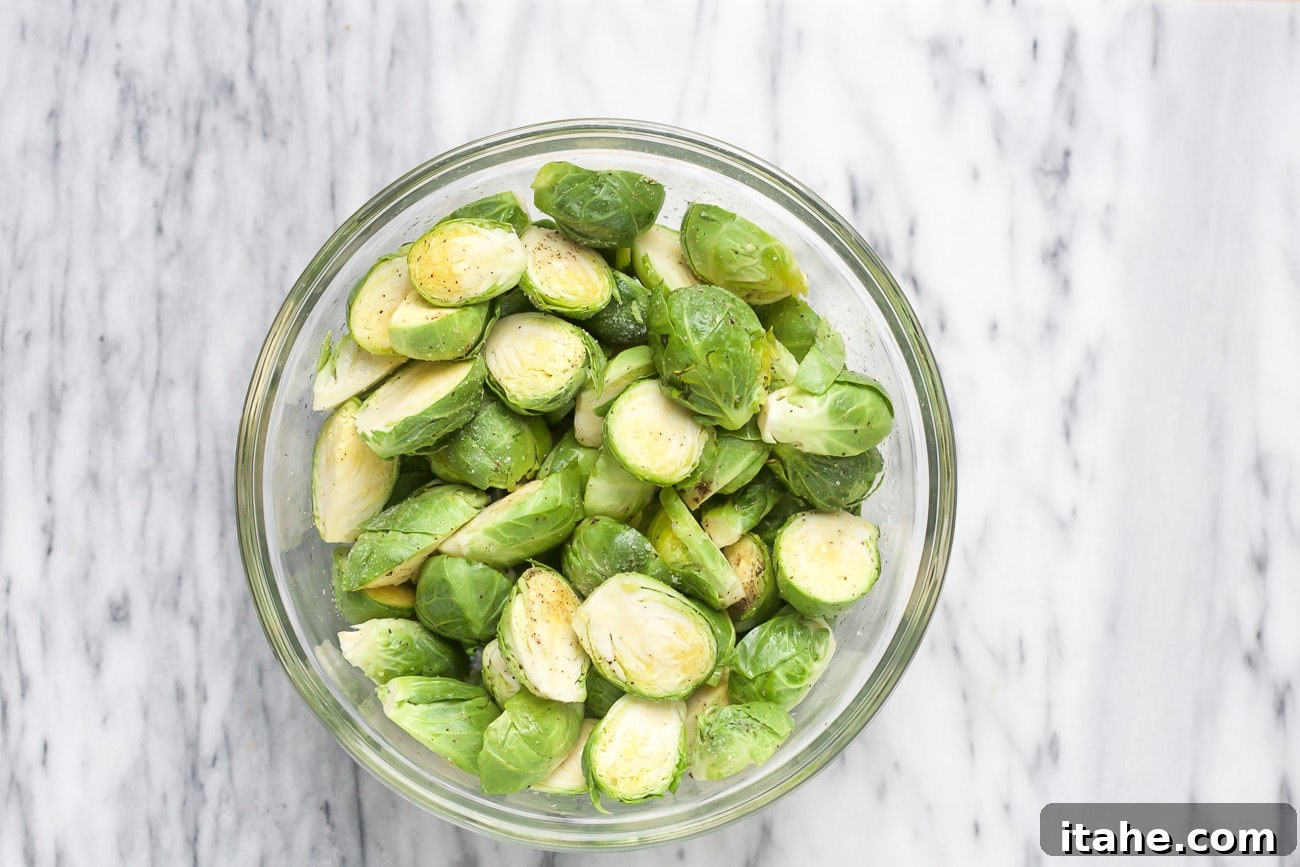 Seasoned Brussels sprouts in a glass bowl, ready for the air fryer.