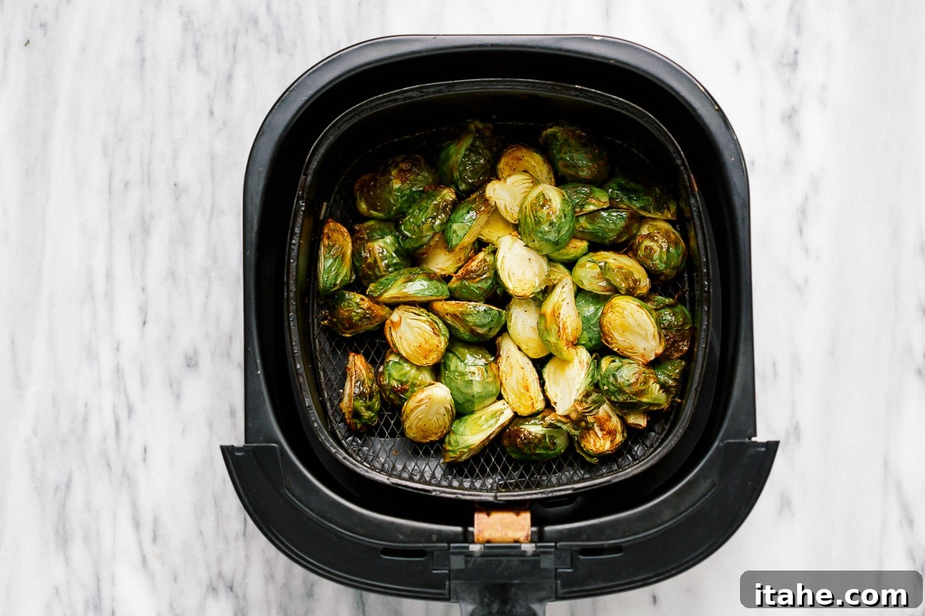 Crispy, cooked Brussels sprouts in a black air fryer basket.