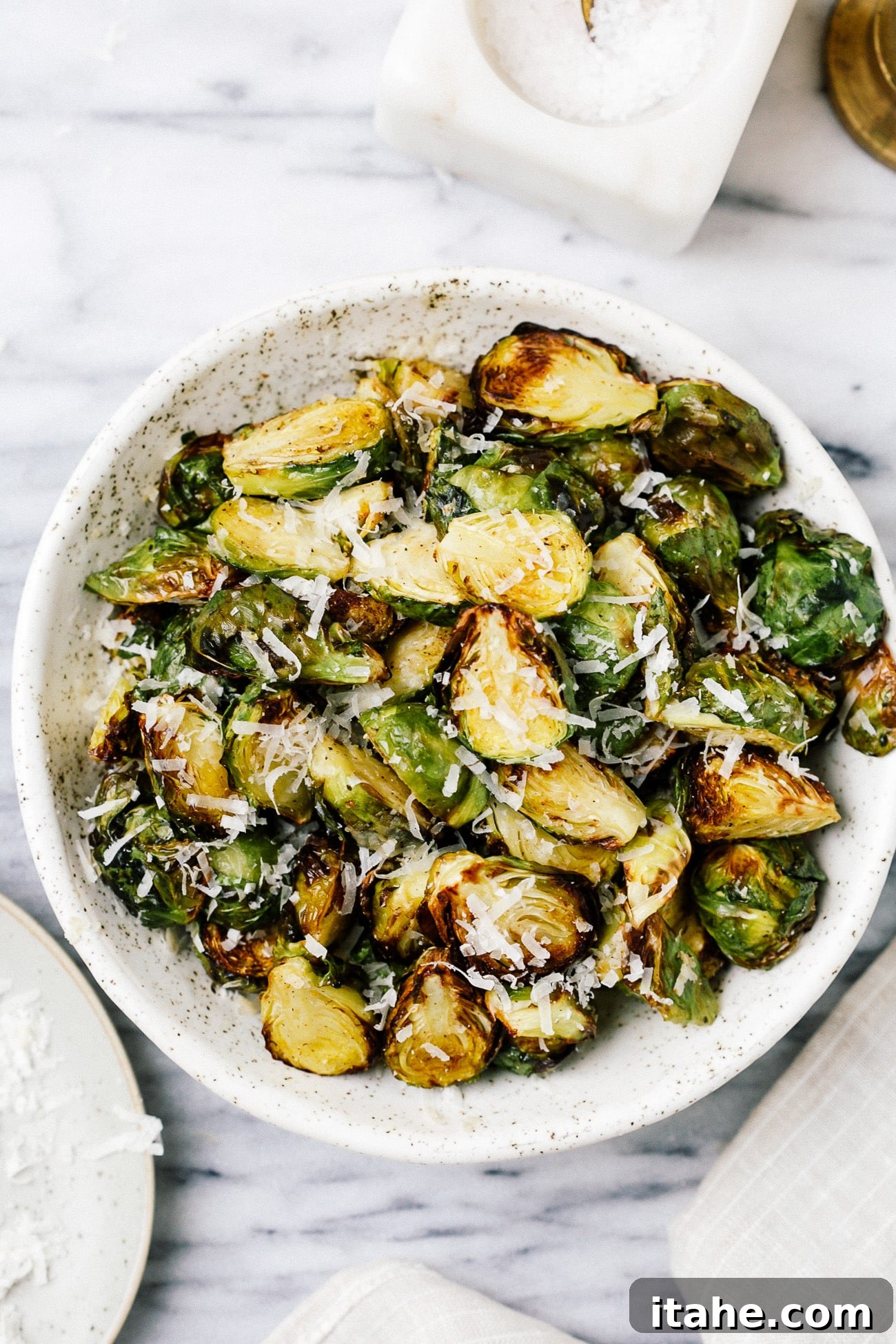 A serving bowl full of crispy Brussels sprouts topped with parmesan cheese, ready to be devoured.