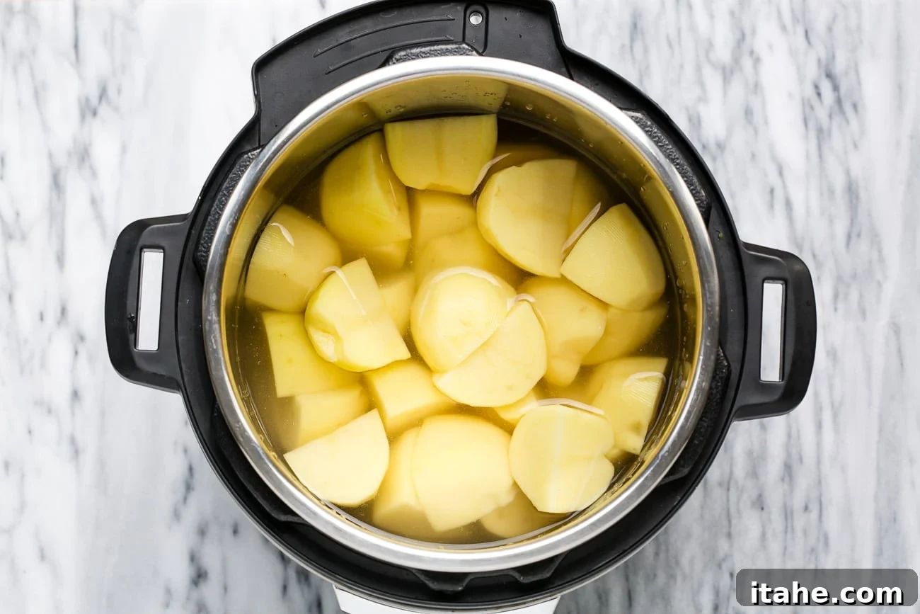 Peeled and quartered potatoes covered in water in an instant pot.