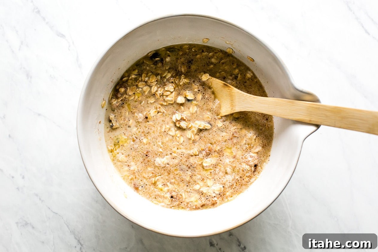 Spiced Apple Raisin Baked Oatmeal 7 The combined wet and dry ingredients forming a thick, luscious baked oatmeal batter with visible raisins and nuts in a large mixing bowl.