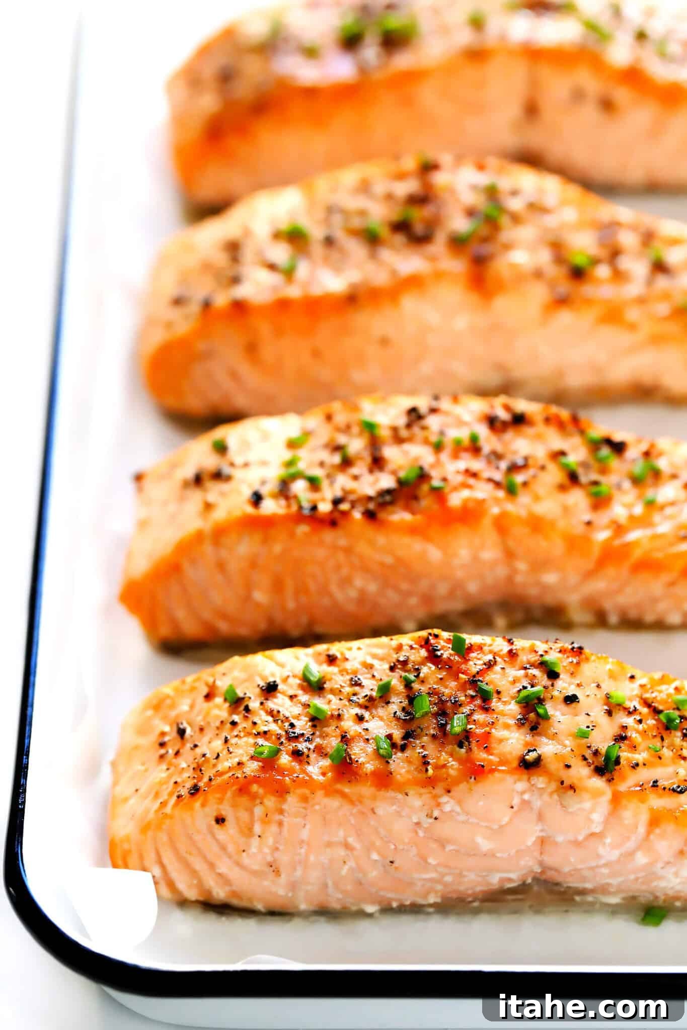Three golden-baked salmon fillets resting on a baking sheet, ready to be served.