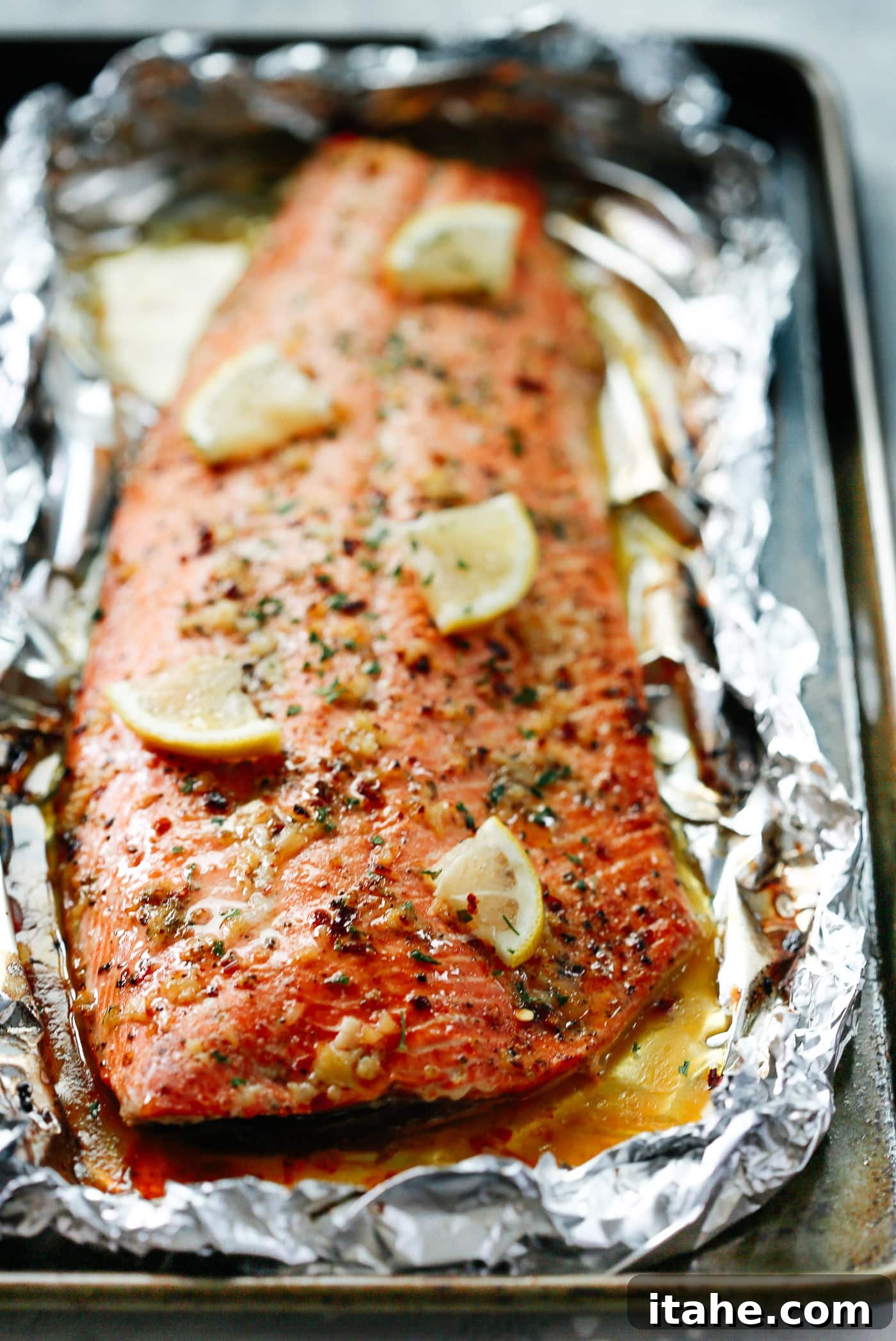 A close-up of a tender salmon fillet cooked in a baking sheet, infused with garlic butter.