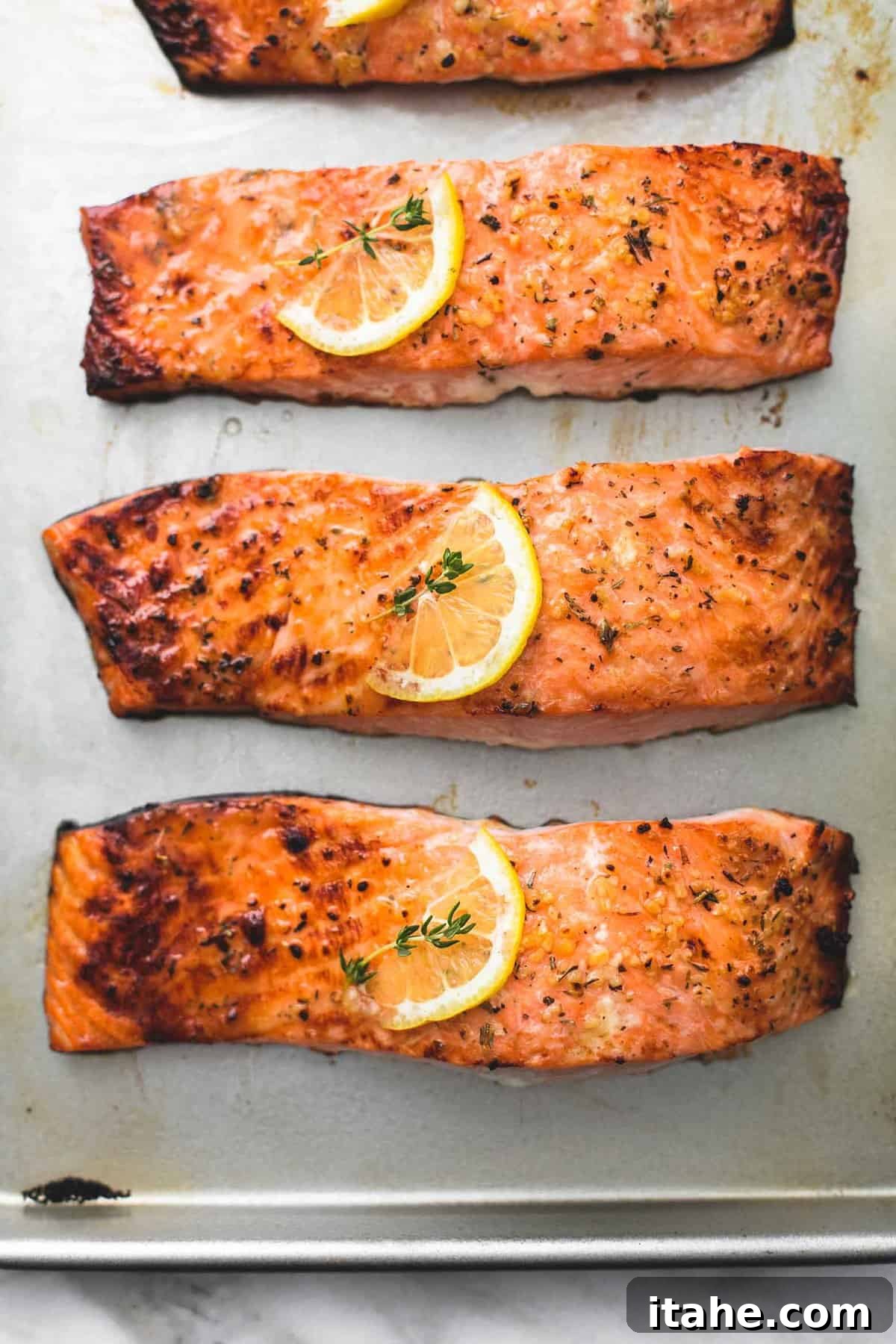 Three perfectly baked salmon fillets on a baking sheet, ready for a healthy meal.