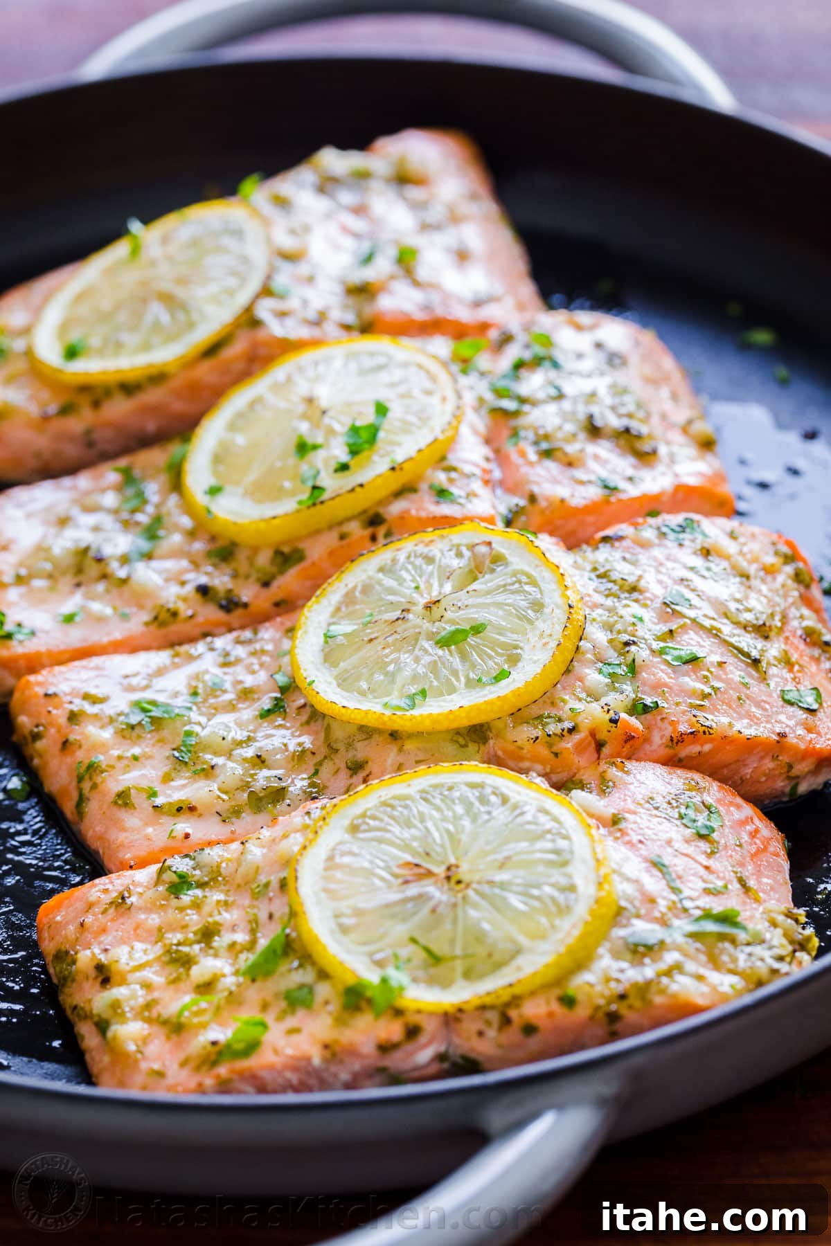 An overhead view of a cast iron skillet with baked salmon, glistening with a garlic and Dijon glaze.
