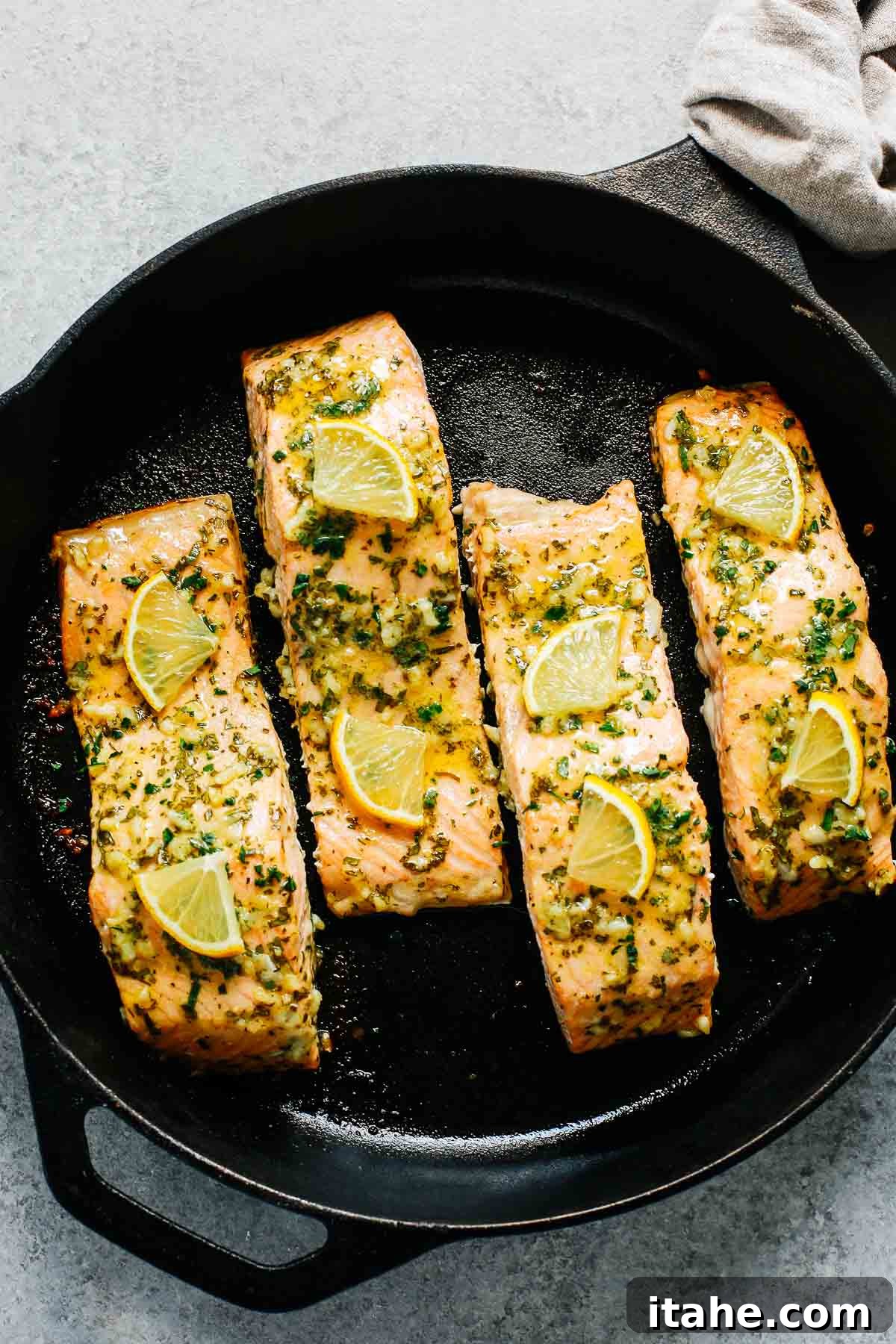 Baked salmon with lemon slices and a rich Dijon sauce in a cast iron skillet.