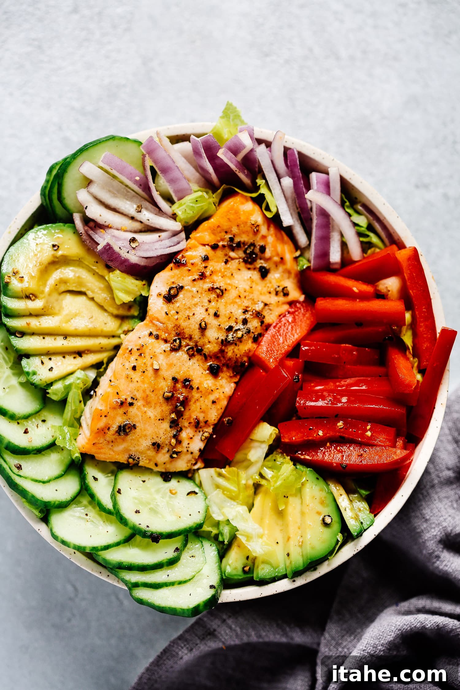 Overhead view of a beautiful salmon salad bowl, packed with fresh ingredients.