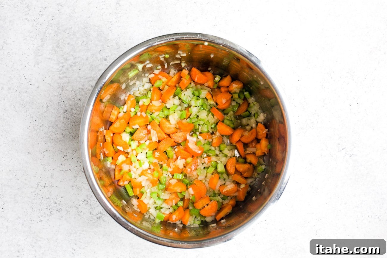 Sautéing diced onion, carrots, and celery in the Instant Pot for mirepoix base.