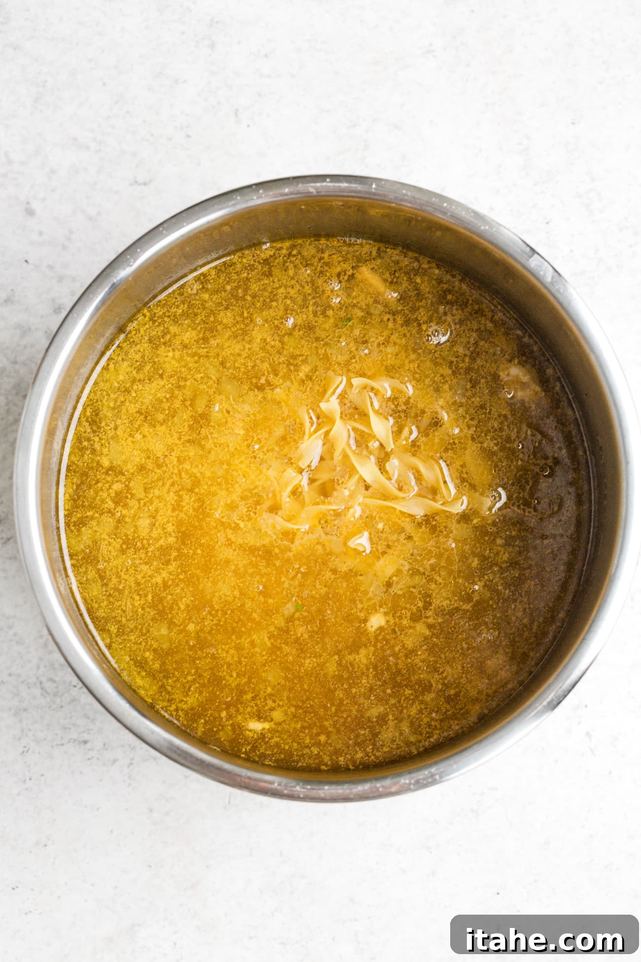 Wide egg noodles added to the Instant Pot with the hot chicken broth and vegetables.