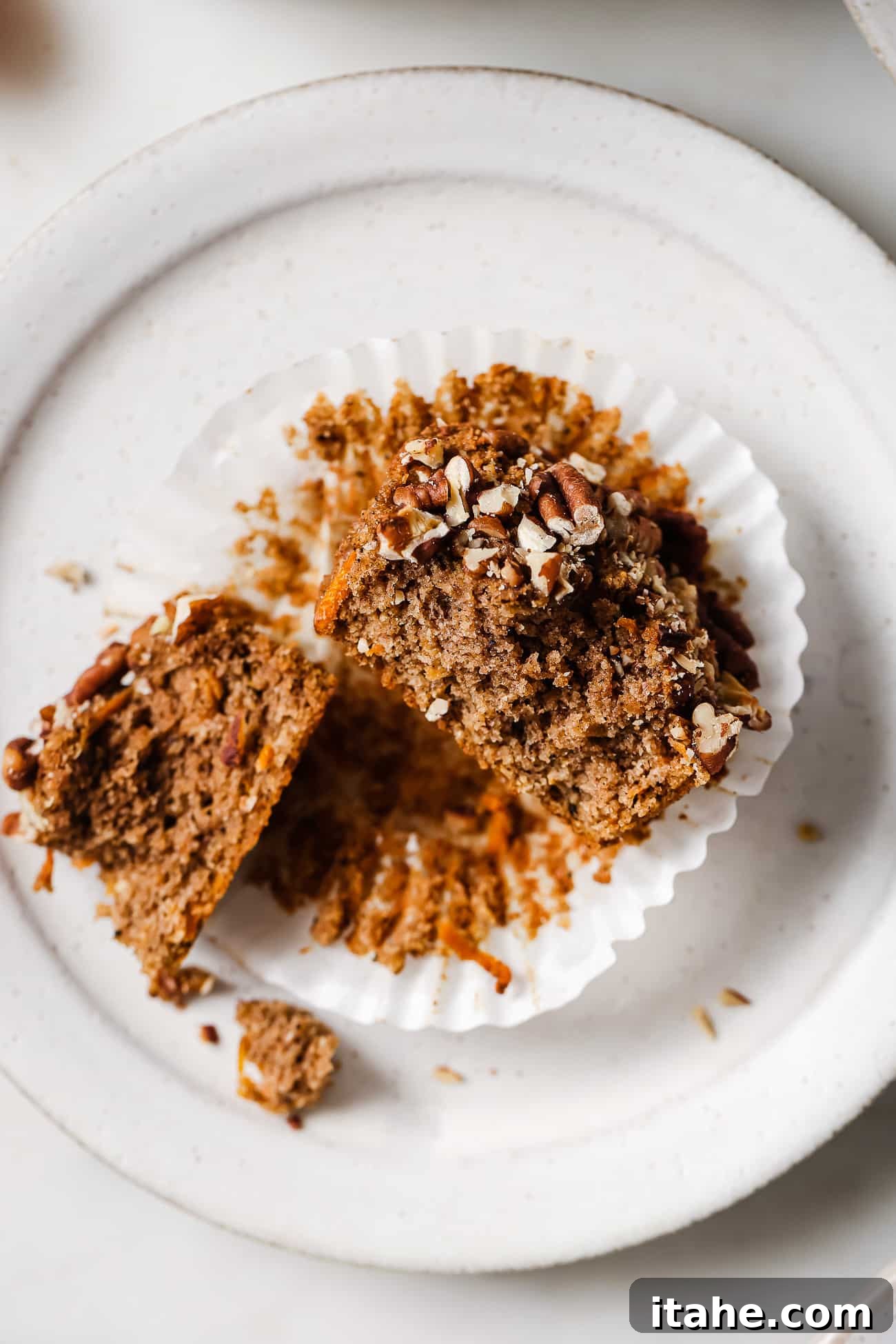 Spiced Gluten-Free Carrot Muffins 6 A gluten-free carrot muffin sliced in half on a white plate.